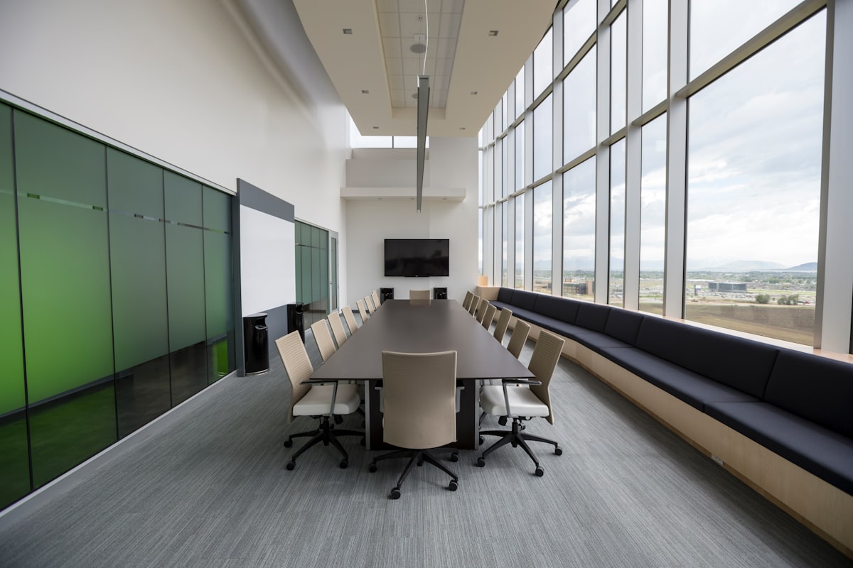 An elegant, empty boardroom with a long wooden table and rows of chairs, no people, for the piece on the gap between AI-agent boardroom announcements and the back-office work that actually pays off