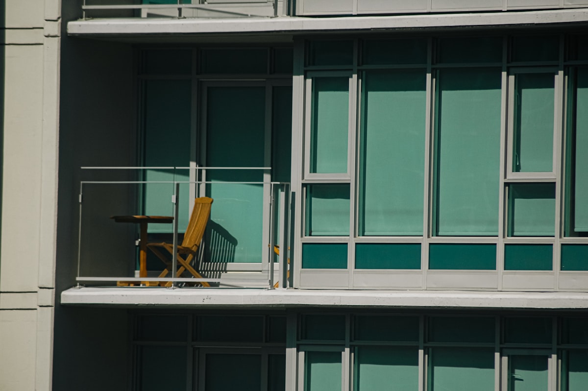 An empty yellow chair on a balcony, no people in frame and no readable brand or logo, for the piece on the asset threshold behind the mini-retirement trend