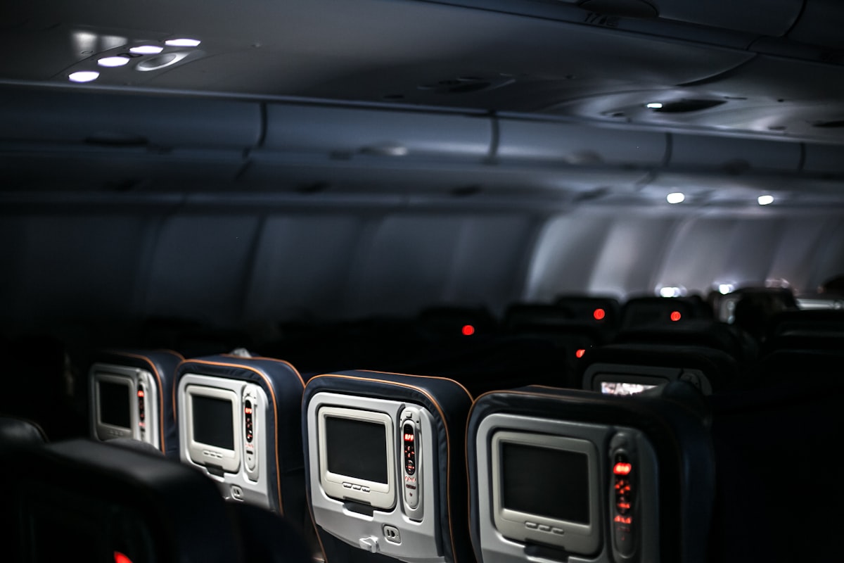 The interior of a single-aisle economy cabin with empty seats and seatback screens, no people and no readable brand or logo, for the piece on narrowbody jets flying new transatlantic routes